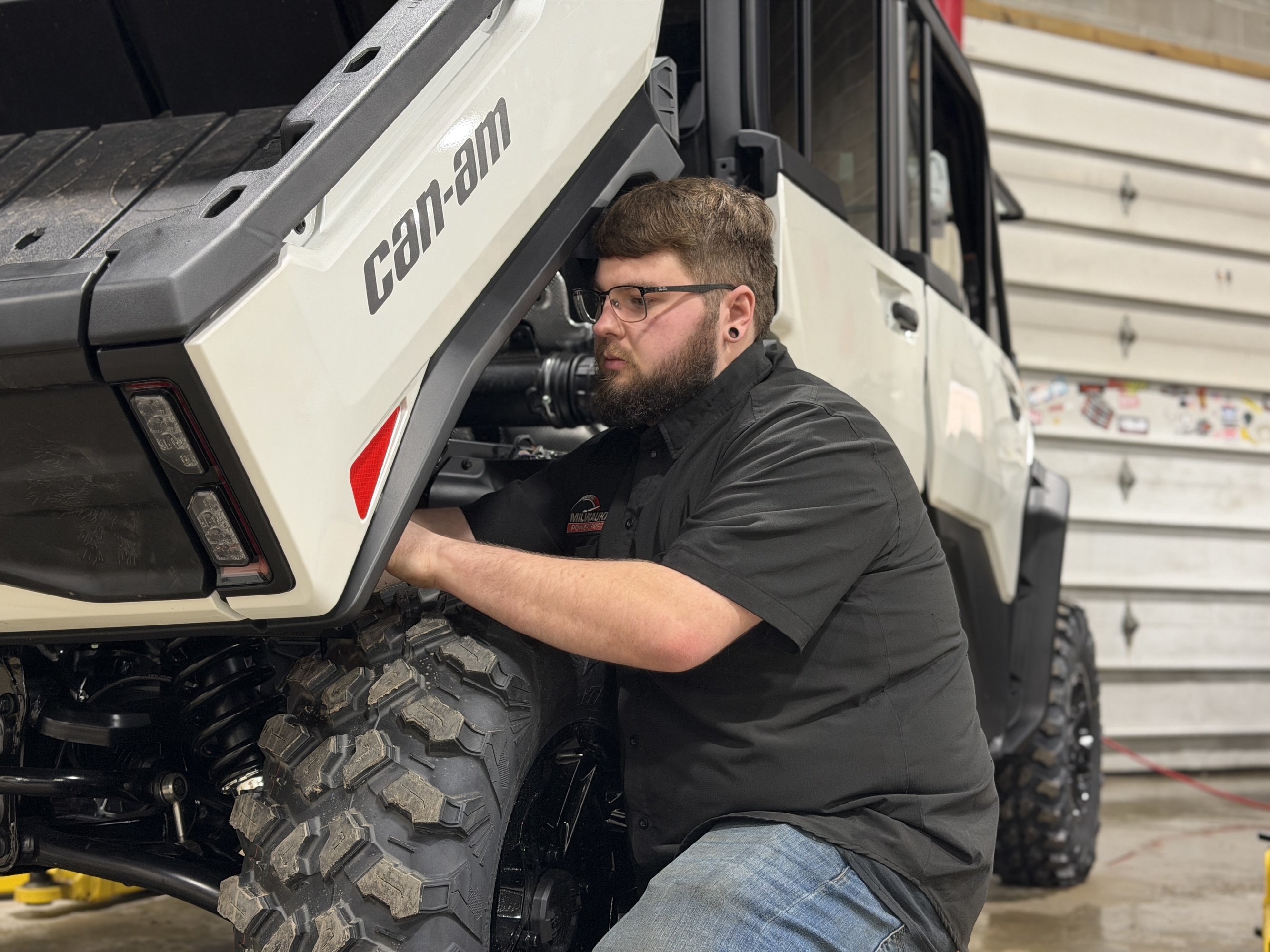a Can-Am certified technician adjusting the dump box on a Can-Am Defender HD11