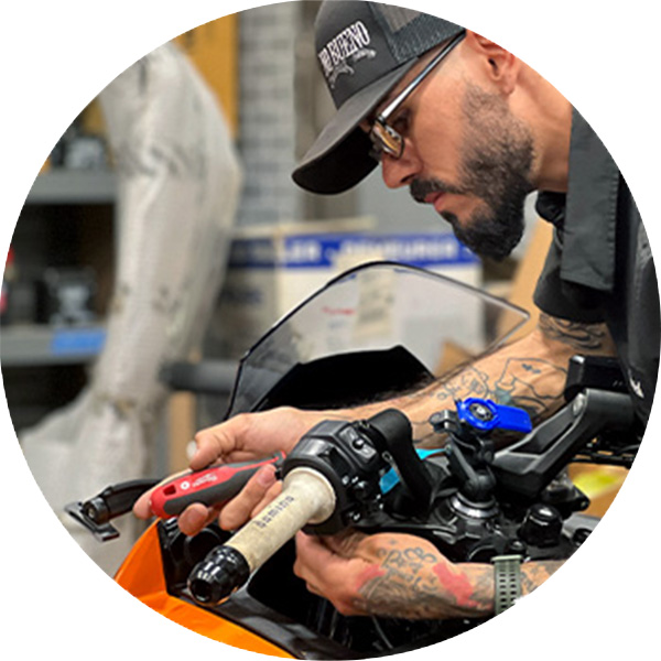 a motorcycle technician adjusting the throttle on a motorcycle